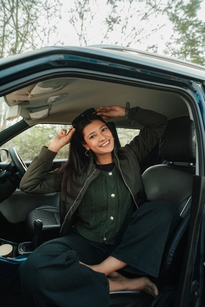Happy woman sitting in car with door open, enjoying break